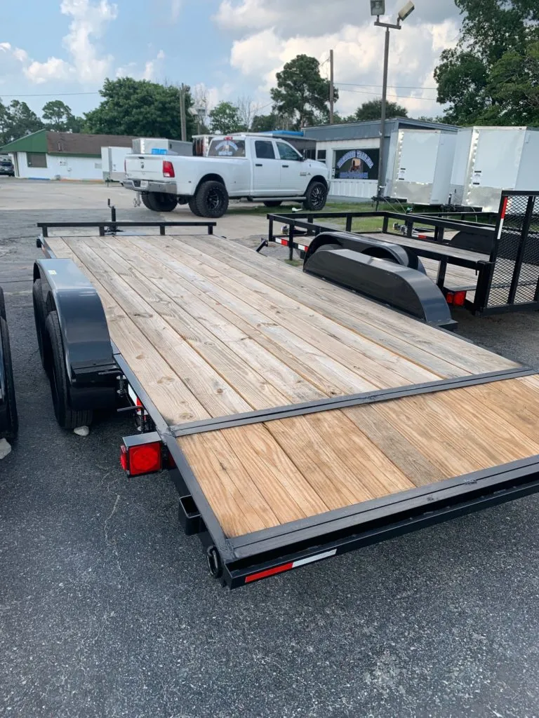 Low-angle rear view of a wooden-deck utility trailer parked on a paved lot