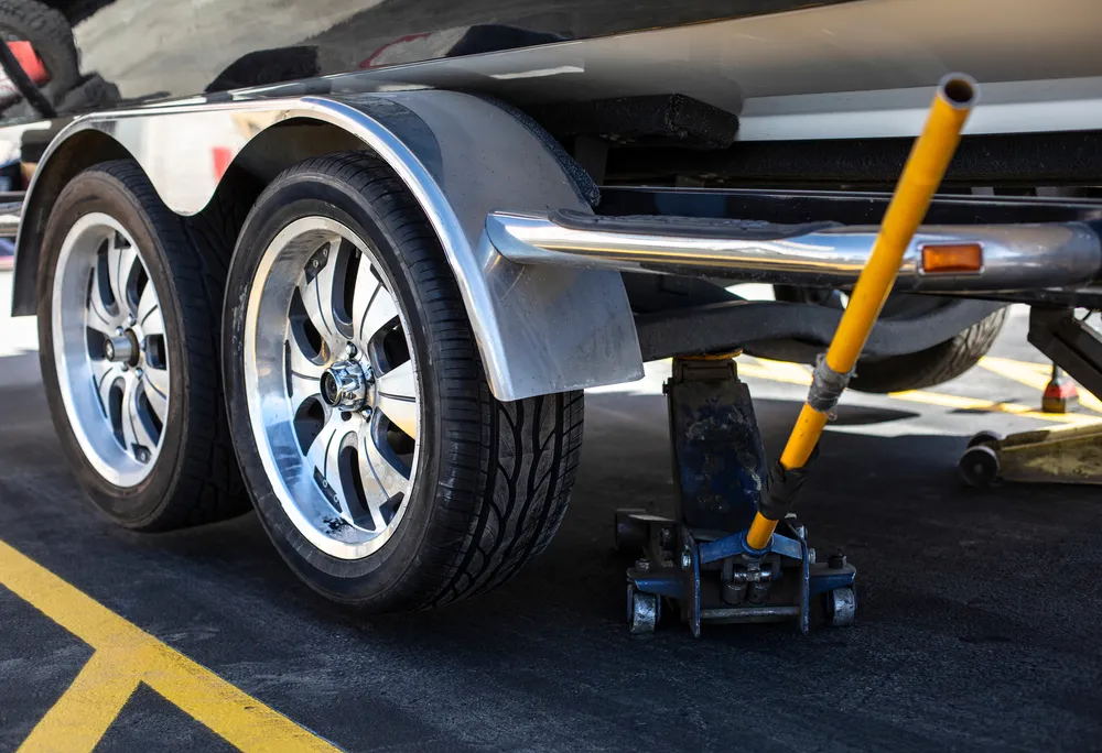 Close up view of a car jack lifting up trailer that just had a new tire installed.